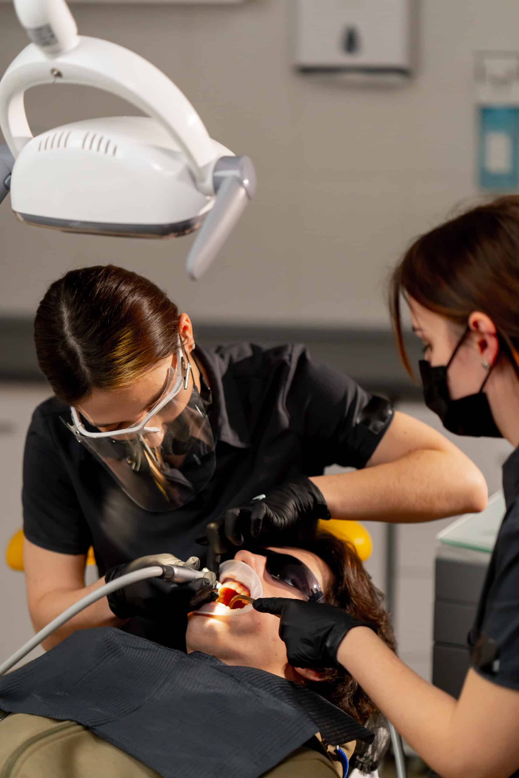 dental office girl dentist doing cleaning to a young guy before the whitening procedure