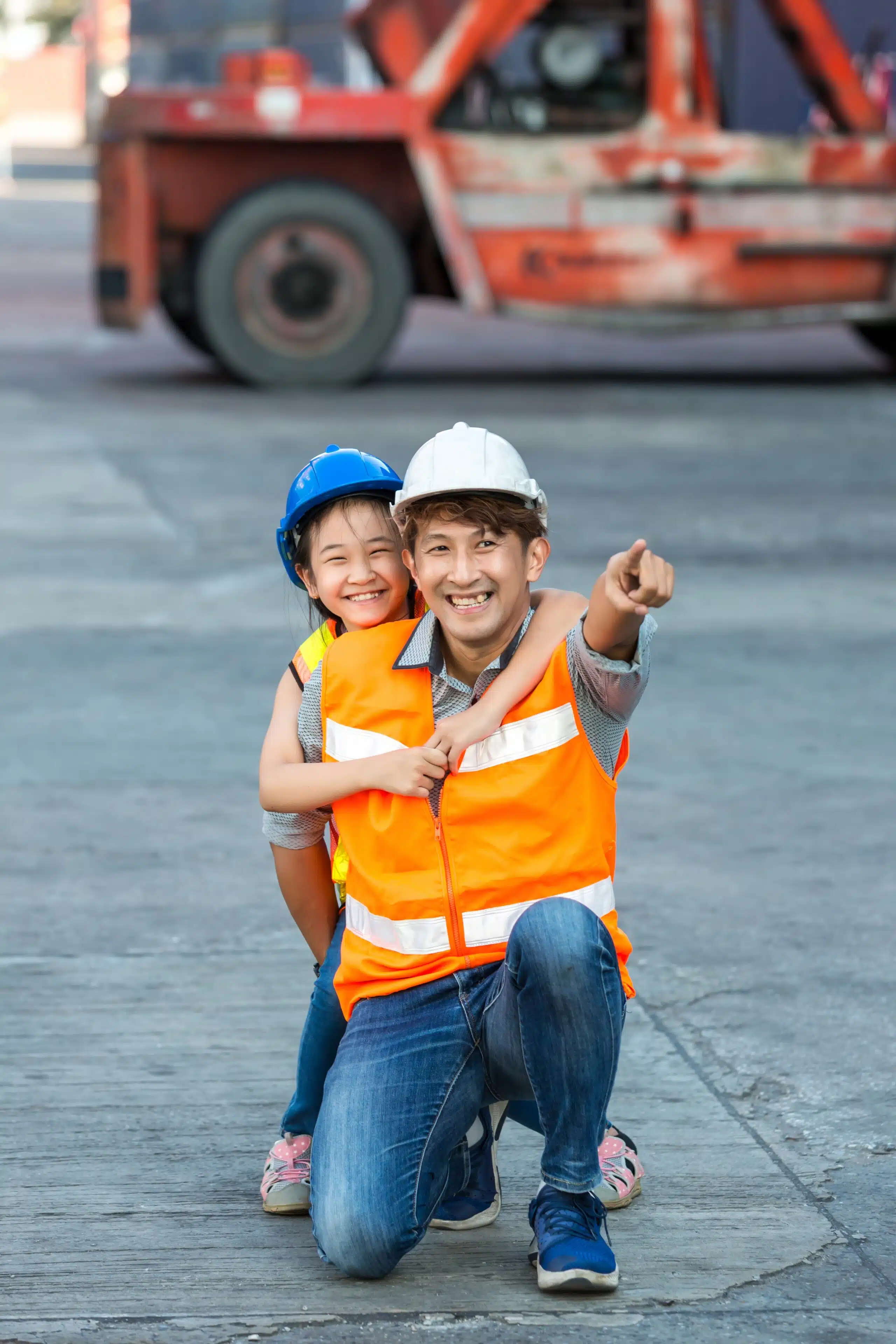 father and little daughter wearing safety helmets looking at what he does for work at a distance