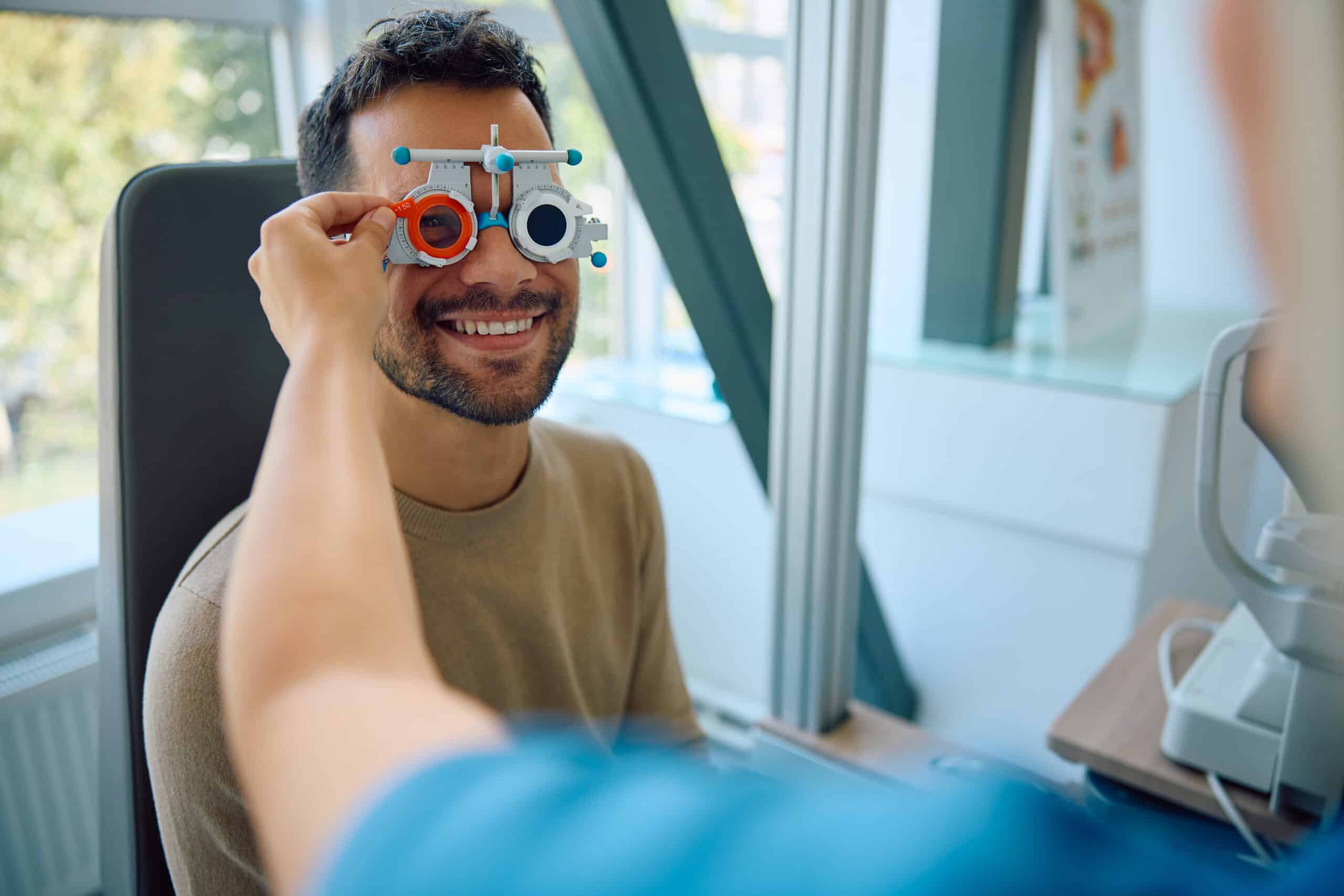 Young happy man with testing eyeglasses at ophthalmologist's.