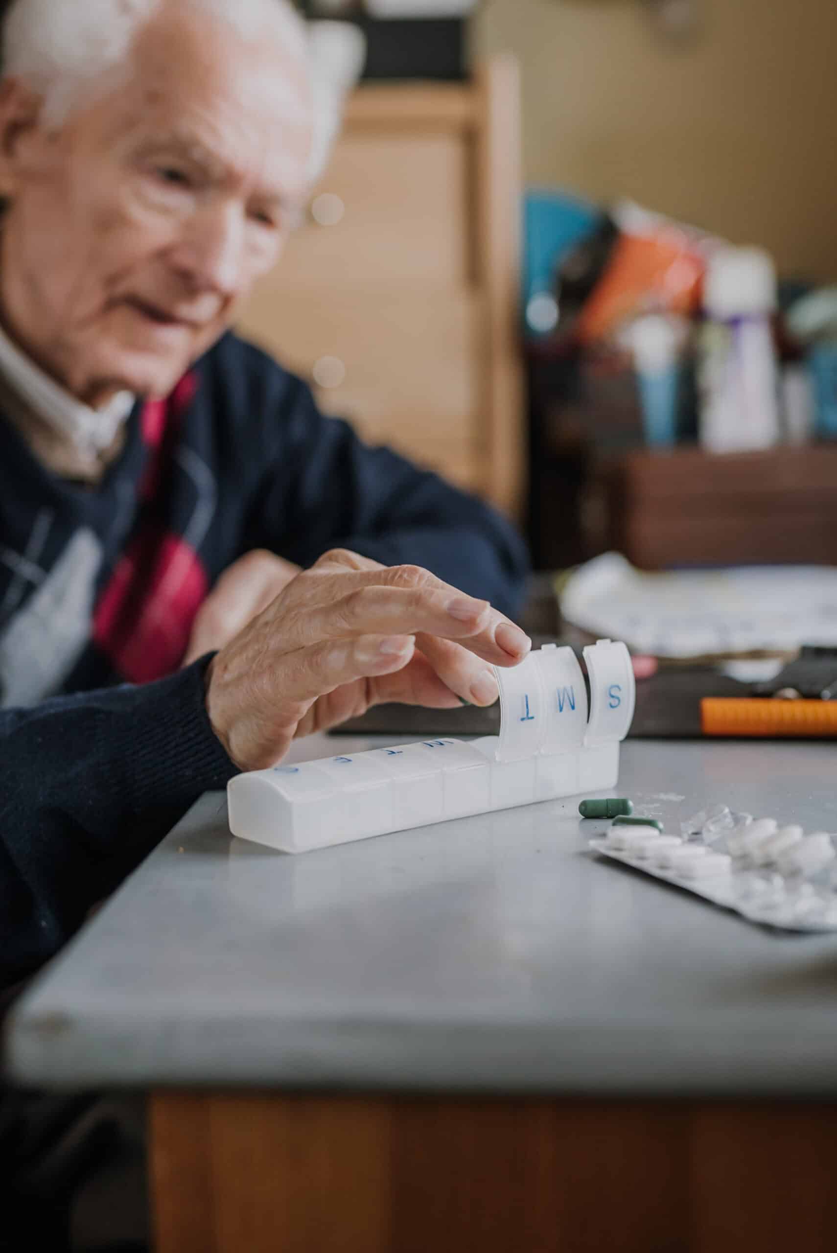 Old man puts tablets in box, organizes medicines for each day of week, Senior takes medicines and tablets during treatment.